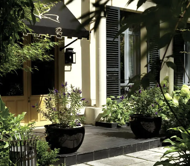 Спокойный сад отеля Regent's Garden (Regent's Garden) в Париже, с столами и стульями, окружёнными зеленью и подстриженными деревьями