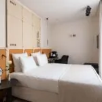 Chambre Double Terrasse Daniel Auteuil avec un lit et une tête de lit en bois à l’hôtel Astra Opéra