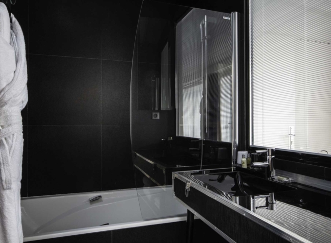 Vue de la salle de bain de la Chambre Familiale Double Privilège avec balcon à l’Hôtel Le 123 Sébastopol avec baignoire et lavabo