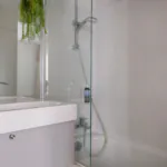 Badezimmer des Doppelzimmers mit einem Waschbecken, einer Badewanne mit Dusche und einem Spiegel im Hotel George