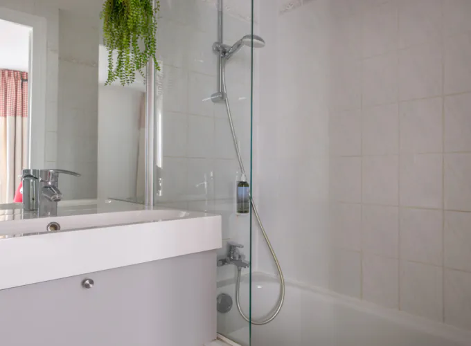 Badezimmer des Doppelzimmers mit einem Waschbecken, einer Badewanne mit Dusche und einem Spiegel im Hotel George