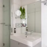 Badezimmer des Doppelzimmers mit einem Waschbecken, einer Badewanne mit Dusche und einem Spiegel im Hotel George