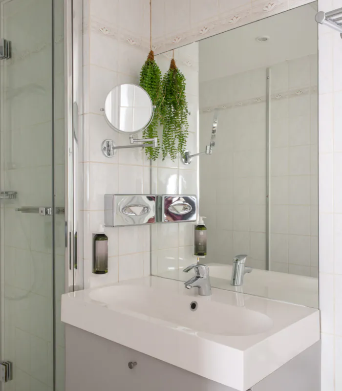 Badezimmer des Doppelzimmers mit einem Waschbecken, einer Badewanne mit Dusche und einem Spiegel im Hotel George