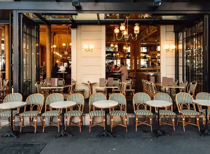 Café typique des Grands Boulevards à Paris, avec façade ouverte, mobilier de bistrot traditionnel et ambiance chaleureuse.