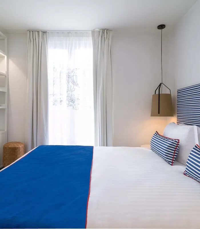 Chambre double avec tête de lit à rayures bleues et blanches à l’Hôtel 34B