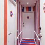 Couloir de la Chambre Familiale avec des rayures rouges, blanches et bleues et le numéro 601 sur la porte à l’Hôtel 34B