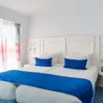 Chambre Familiale avec deux lits et des oreillers bleus à l’Hôtel 34B