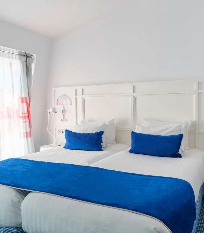 Chambre Familiale avec deux lits et des oreillers bleus à l’Hôtel 34B