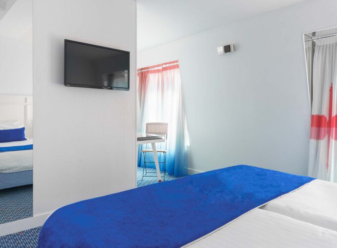 Chambre Familiale avec deux lits et une télévision à écran plat à l’Hôtel 34B