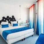 Chambre Familiale Supérieure avec un grand lit et des rideaux bleus à l’Hôtel 34B