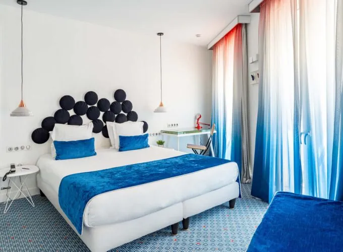 Chambre Familiale Supérieure avec un grand lit et des rideaux bleus à l’Hôtel 34B