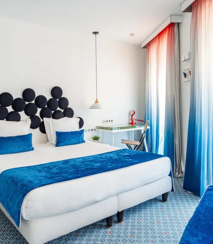 Chambre Familiale Supérieure avec un grand lit et des rideaux bleus à l’Hôtel 34B