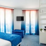 Chambre Familiale Supérieure avec des rideaux bleus et une télévision à écran plat à l’Hôtel 34B