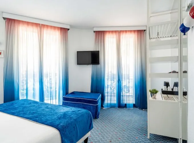 Chambre Familiale Supérieure avec des rideaux bleus et une télévision à écran plat à l’Hôtel 34B