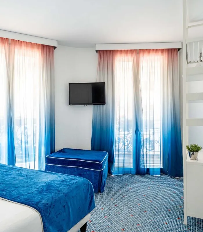 Chambre Familiale Supérieure avec des rideaux bleus et une télévision à écran plat à l’Hôtel 34B