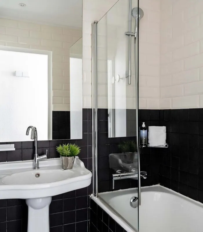 Salle de bain de la Chambre Familiale Supérieure avec des carreaux noirs et blancs et un lavabo à l’Hôtel 34B