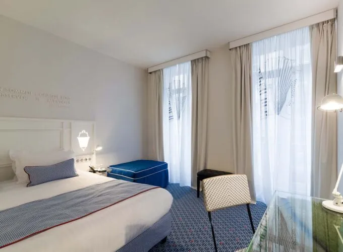 Chambre Privilège avec un lit blanc et un pouf bleu à l’Hôtel 34B