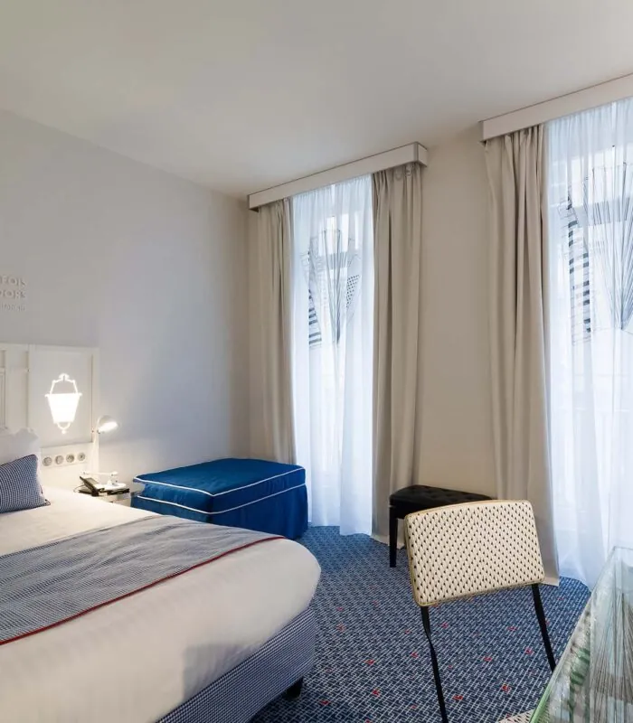 Chambre Privilège avec un lit blanc et un pouf bleu à l’Hôtel 34B