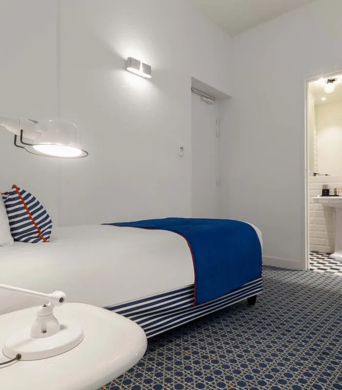 Chambre triple avec une couverture à rayures bleues et blanches sur le lit à l’Hôtel 34B