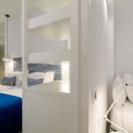 Chambre triple avec un lit bleu et des oreillers blancs à l’Hôtel 34B