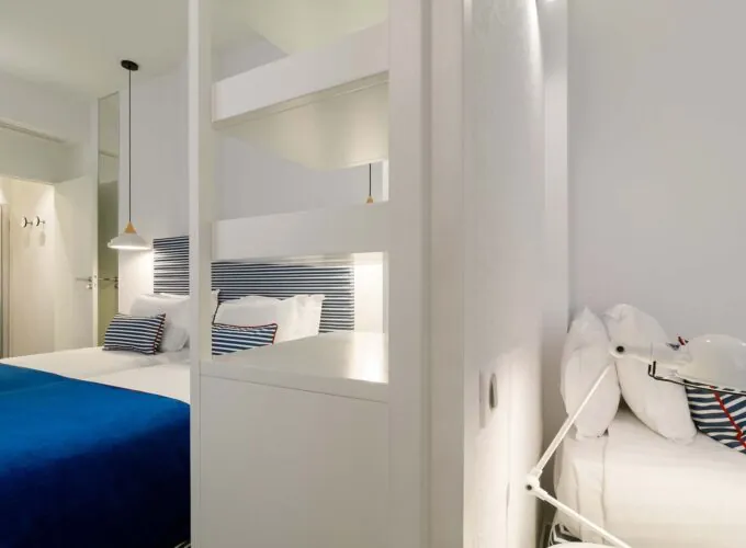 Chambre triple avec un lit bleu et des oreillers blancs à l’Hôtel 34B