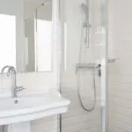 Salle de bain de la chambre triple avec un lavabo, un miroir et une douche à l’Hôtel 34B