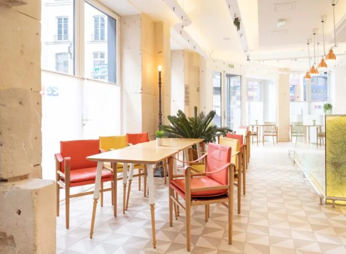 Salle Marianne avec tables, chaises et panneau à l’hôtel 34B