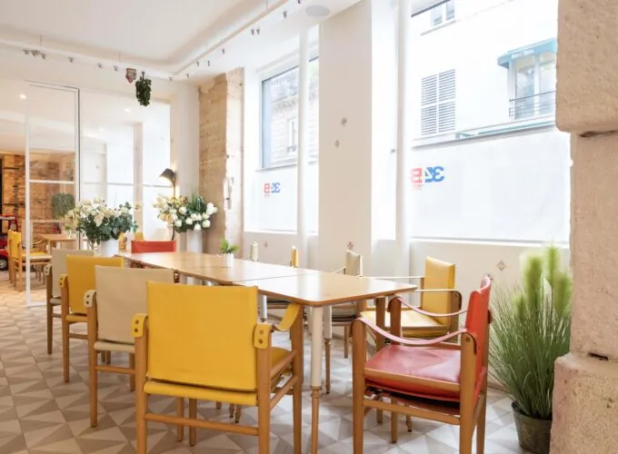 Salle Marianne avec tables, chaises et panneau à l’hôtel 34B