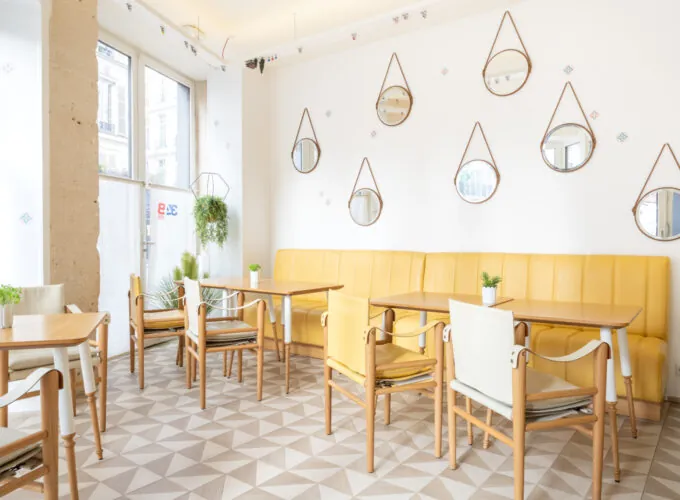 Salle Marianne avec tables, chaises et miroirs à l’Hôtel 34B