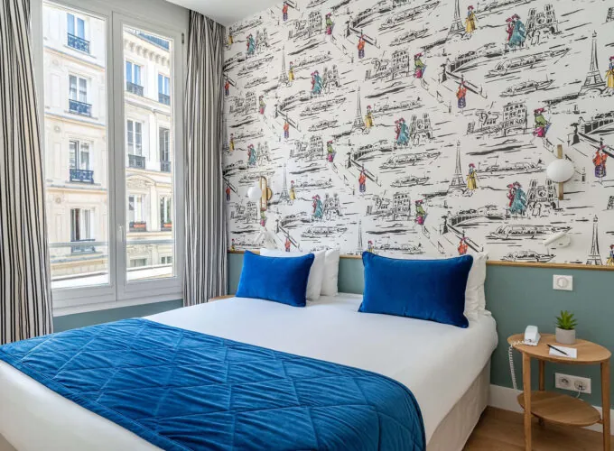 Chambre Double avec un lit et des oreillers bleus à l’hôtel Acadia