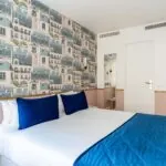 Chambre Double avec un lit et des oreillers bleus à l’hôtel Acadia