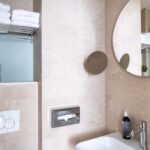 Chambre Double avec salle de bain comprenant un lavabo et un miroir rond à l’hôtel Acadia