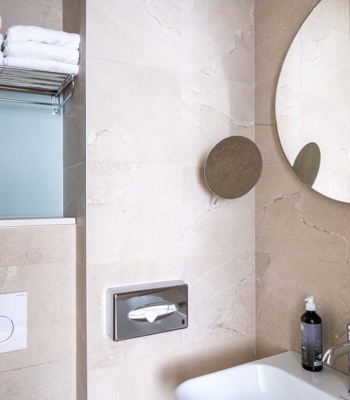 Chambre Double avec salle de bain comprenant un lavabo et un miroir rond à l’hôtel Acadia