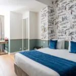 Chambre familiale avec un lit et des oreillers bleus à l’Hôtel Acadia