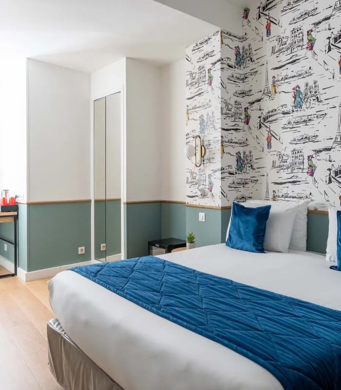 Chambre familiale avec un lit et des oreillers bleus à l’Hôtel Acadia