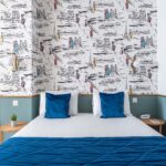 Lit d’une chambre familiale avec des oreillers bleus devant un mur décoré de dessins à l’Hôtel Acadia