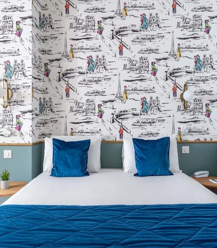 Lit d’une chambre familiale avec des oreillers bleus devant un mur décoré de dessins à l’Hôtel Acadia