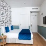 Chambre familiale avec une couverture bleue sur le lit à l’Hôtel Acadia