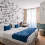 Chambre familiale avec deux lits et un bureau à l’Hôtel Acadia