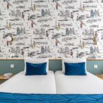 Chambre familiale avec deux lits et une couverture bleue à l’Hôtel Acadia