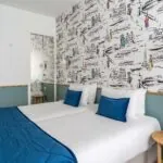 Chambre familiale avec deux lits et un papier peint coloré à l’Hôtel Acadia