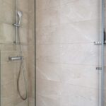 Salle de bain d’une chambre familiale avec une douche et une plante sur l’étagère à l’Hôtel Acadia