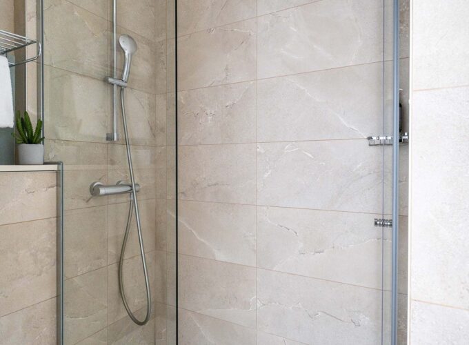 Salle de bain d’une chambre familiale avec une douche et une plante sur l’étagère à l’Hôtel Acadia