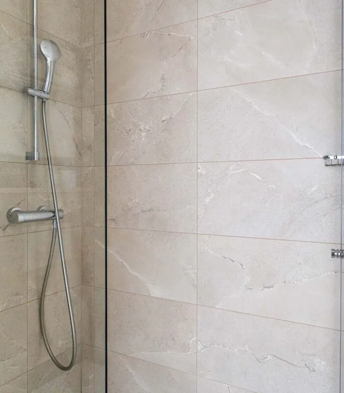 Salle de bain d’une chambre familiale avec une douche et une plante sur l’étagère à l’Hôtel Acadia