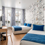 Chambre Triple avec deux lits et un bureau à l’hôtel Acadia