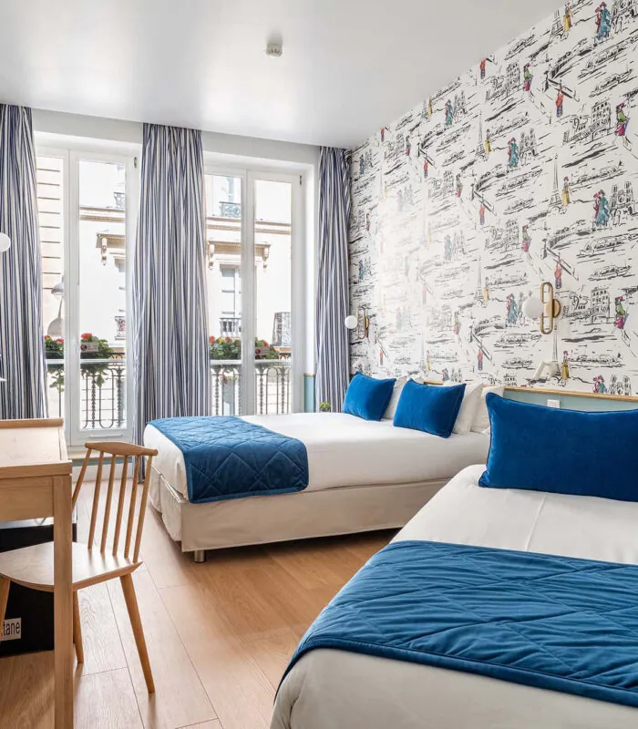 Chambre Triple avec deux lits et un bureau à l’hôtel Acadia