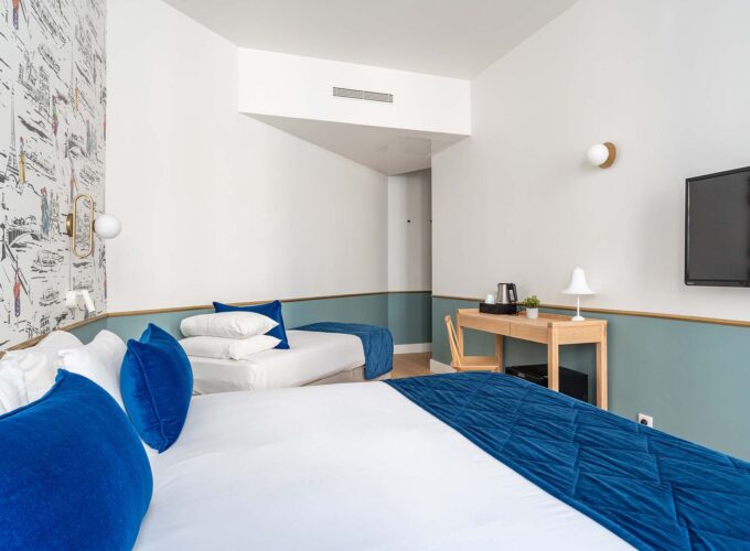 Chambre Triple avec deux lits et une télévision à écran plat à l’hôtel Acadia