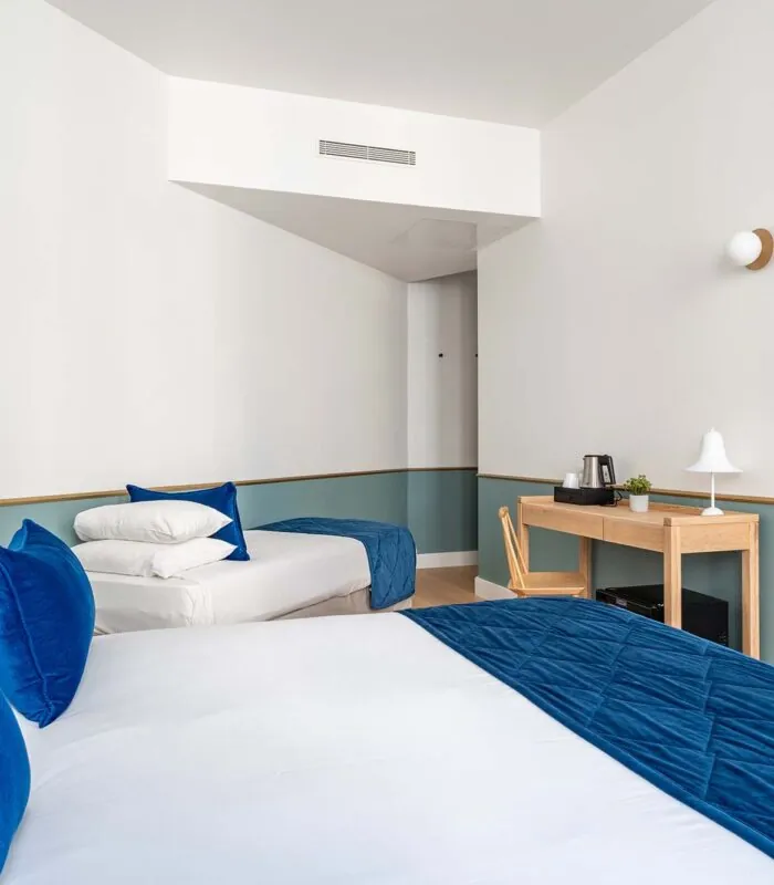 Chambre Triple avec deux lits et une télévision à écran plat à l’hôtel Acadia