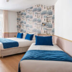 Chambre Triple avec deux lits et des oreillers bleus à l’hôtel Acadia