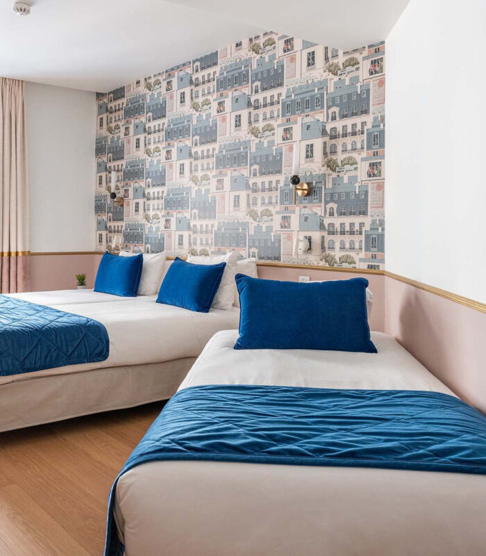 Chambre Triple avec deux lits et des oreillers bleus à l’hôtel Acadia